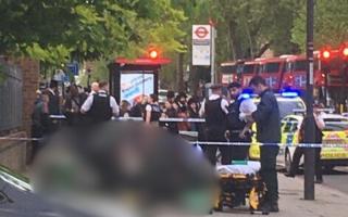 Police at Stamford Hill while paramedics treat a woman
