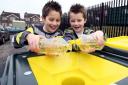Brothers nine-year-old Jack (left) and Tommy, seven, pour used cooking oil into a recycling bin so it can be converted into renewable energy.