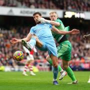 Manchester City's Ruben Dias (left) and Arsenal goalkeeper Aaron Ramsdale battle for the ball