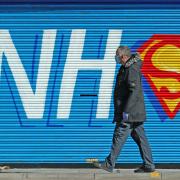 A man walks past a sign created in support of the NHS during the pandemic