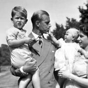A photo dated August, 9, 1951, of the Princess Royal in the arms of Queen Elizabeth II, with The Duke of Edinburgh, holding The Prince of Wales, in the grounds of Clarence House.