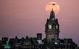 The moon sets behind the Balmoral Clock in Edinburgh